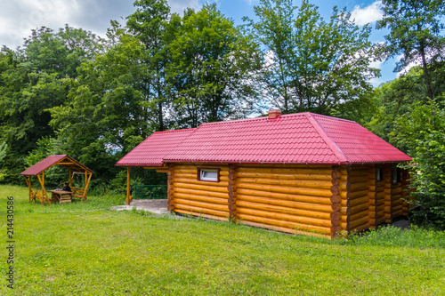 The house consists of a wooden frame with small windows and a red roof located near the gazebo