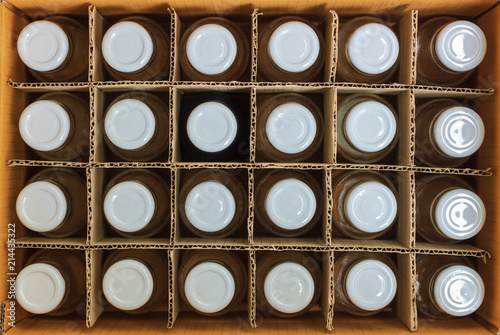 Glass bottles with white bottle caps in a cardboard box, Top view, Packaging concept.