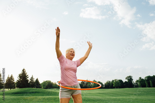 elderly woman does the exercise with hula hoops, laughing and enjoy the rest at park