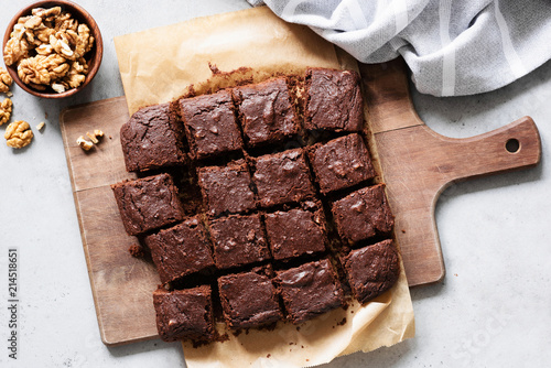 Chocolate brownie squares with walnuts on cutting board, top view, horizontal composition. Flat lay food