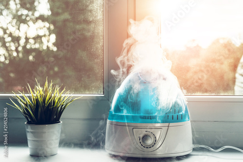Air humidifier during work. The white humidifier moistens dry air. Improving the comfort of living in the home, apartment. Improving the well-being of people.