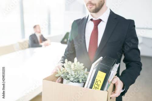 Mid section portrait of handsome businessman holding box of personal belongings leaving office after quitting job, copy space