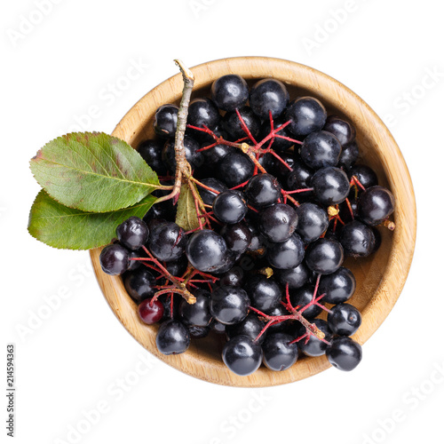 Black chokeberry berries ( Aronia melanocarpa ) in wooden bowl isolated on white