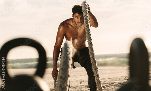 Man doing workout with battle ropes and kettlebells