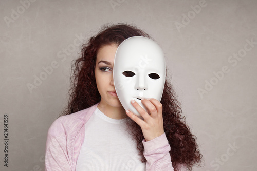sad young woman hiding her face behind mask, identity or personality concept