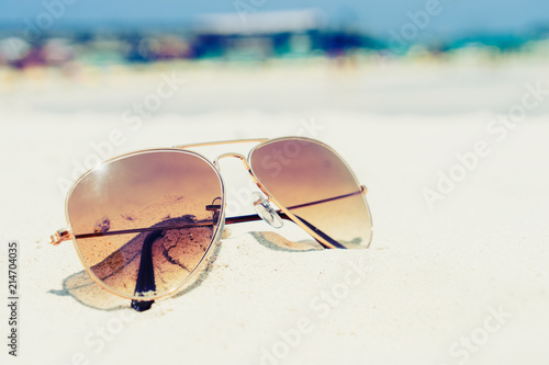 Vintage photo of nostalgia in summer - sunglasses on sand beach. retro film filter effect