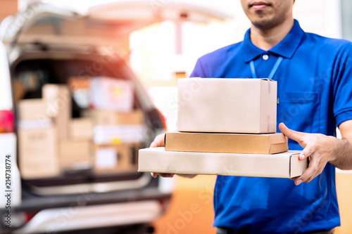 Delivery man holding package in front of cargo van delivering package.