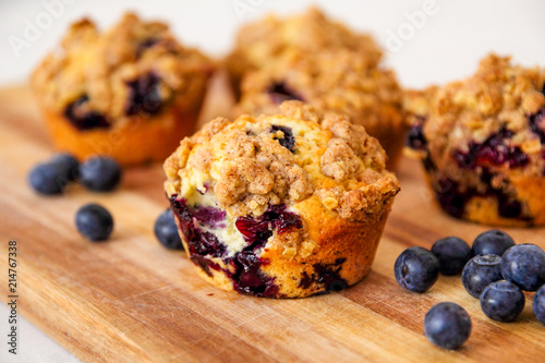 freshly baked blueberry muffins with an oat crumble topping on a natural wooden board