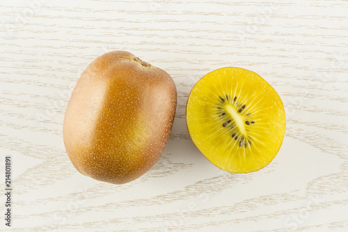 Group of one whole one half of fresh golden brown kiwi fruit sungold variety flatlay on grey wood