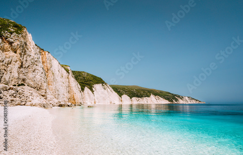 Fteri beach in Kefalonia Island, Greece. One of the most beautiful untouched pebble beach with pure azure emerald sea water surrounded by high white rocky cliffs of Kefalonia