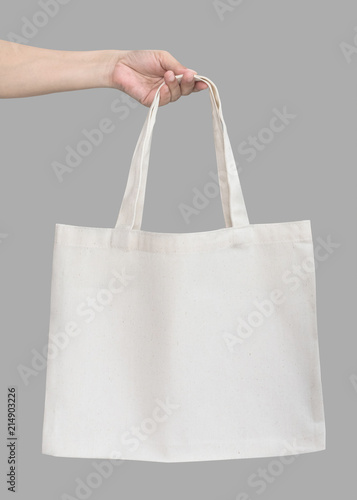 Tote bag canvas white cotton fabric cloth eco shopping sack mockup blank template isolated on grey background (clipping path) with woman’s handling hand