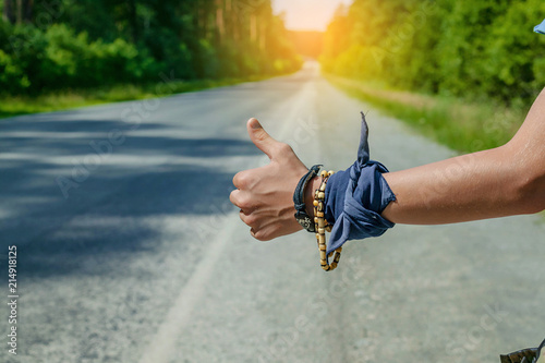 Teenager hitchhiker holding hand gesture to stop a car. Close-up