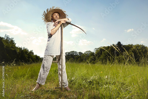 Village natural country man on summer meadow mowing grass with classic scythe