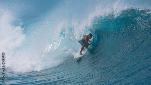 CLOSE UP: Spectacular shot of young surfboarder riding a big emerald tube wave.