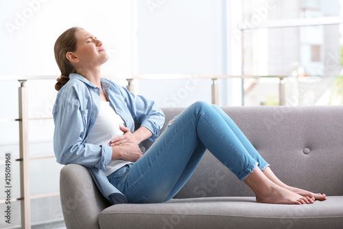 Young woman suffering from menstrual cramps at home. Gynecology