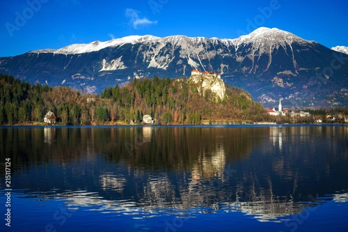 Old medieval castle on the rock against the snowy mountains and the blue sky, Lake Bled, Slovenia
