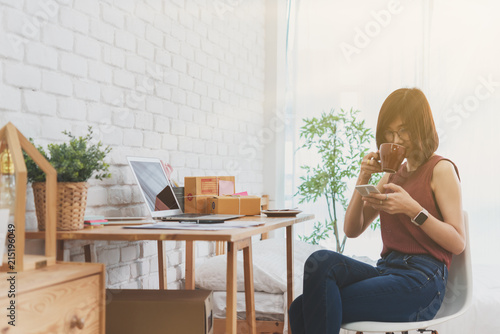 Woman small business owner, business start up conceptual, young entrepreneur use internet with smartphone during morning coffee