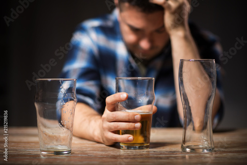 alcoholism, alcohol addiction and people concept - male alcoholic drinking beer from glass at night