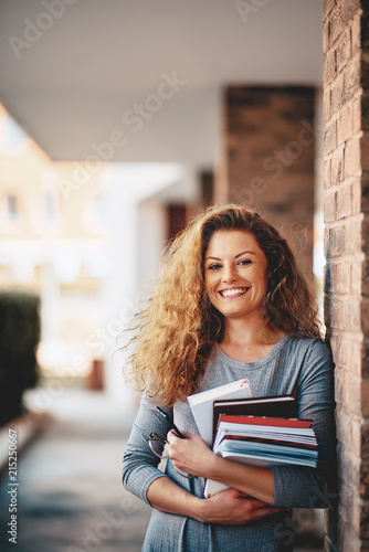 Girl standing against the brick wall and holding book.