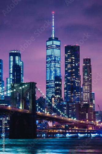 Skyline of downtown New York City Brooklyn Bridge and skyscrapers over East River illuminated with lights at dusk after sunset view from Brooklyn
