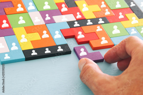 image of tangram puzzle blocks with people icons over wooden table ,human resources and management concept.