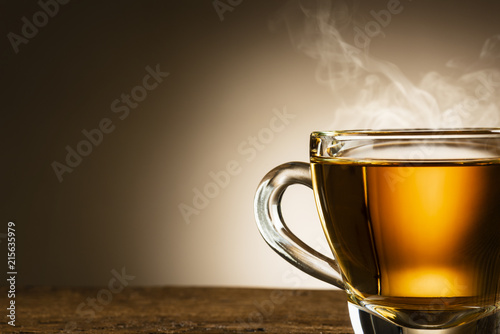 closeup of steamed glass cup of tea on wooden table