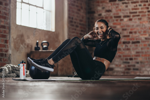 Smiling female in the gym doing sit-up