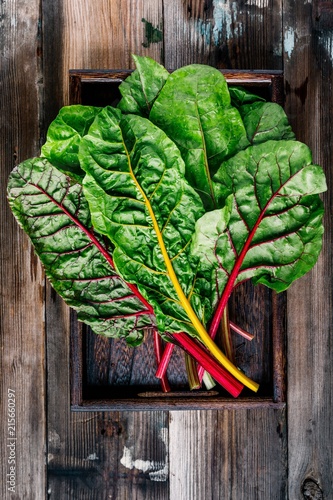 Fresh raw swiss rainbow chard leaves on wooden background.