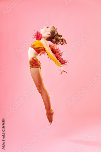 Taniec współczesny. Mała dziewczynka wykonuje skomplikowany taniec akrobatyczny. Taniec nowoczesny na jasnym kolorowym tle.