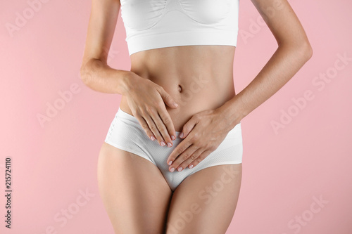 Young woman holding hands near panties on color background. Gynecology concept