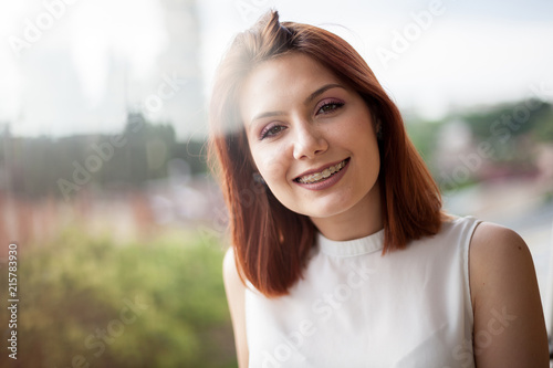 Portrait of gorgeous redhaired woman in summer rays at a balcony