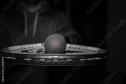 Single dot squash ball on the strings of a racquet