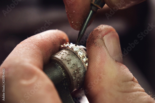 Close up of the hands of a goldsmith while he is making a diamond ring. Concept: jewelry, gold, fashion