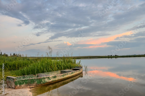 Breathtaking summer scenery with old wooden boat in warm evening sunlight.