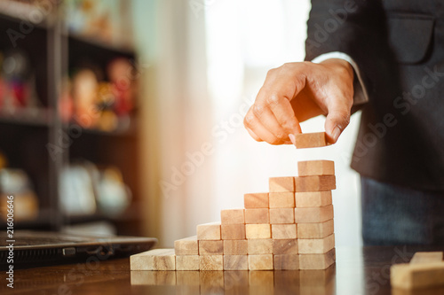 plan and strategy in business.risk concept.hand of man has piling up and stacking a wooden block.Businessman Building The Success.