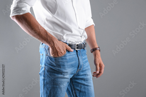 Man in stylish blue jeans on grey background