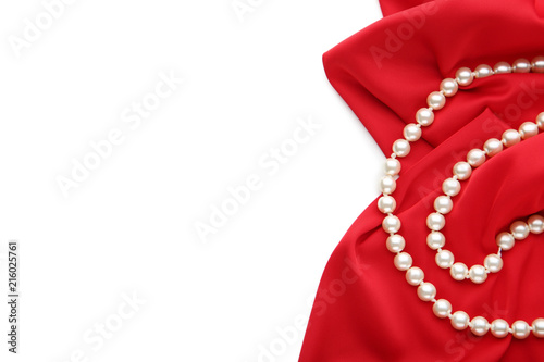 Pearl necklace with red satin fabric on white background