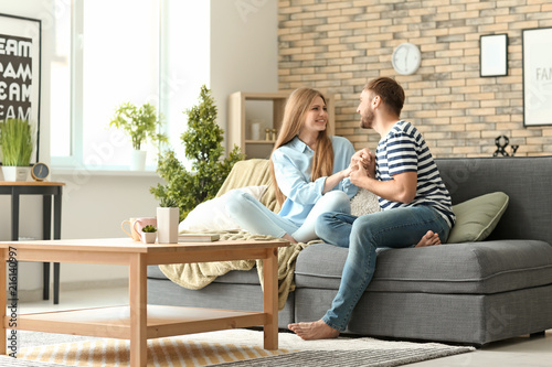 Happy young couple resting on sofa at home