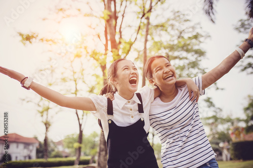 two asian teenager laughing with happiness emotion in green natural park