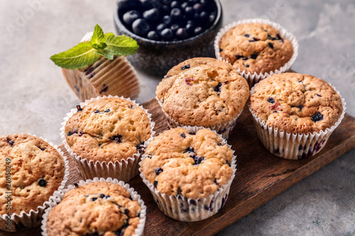 Wooden board with tasty blueberry muffins on table