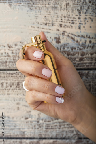 womens perfume MONTALE in a womans hand with a beautiful pink manicure
