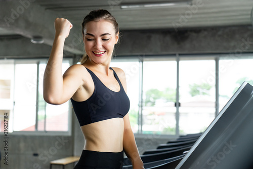 Cute young woman exercising on treadmill at a gym.Active young woman running on treadmill. smile and funny emotion.
