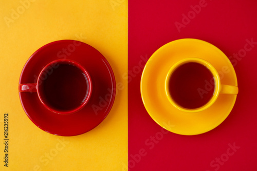 Tea in cups on different backgrounds. Yellow and red cups of tea pairs on yellow and red backgrounds. View from above. Contrast of different colors.
