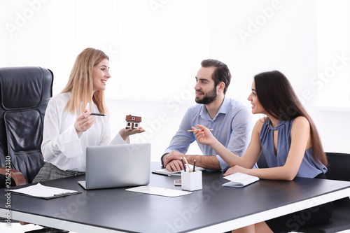 Real estate agent showing house model to clients in office