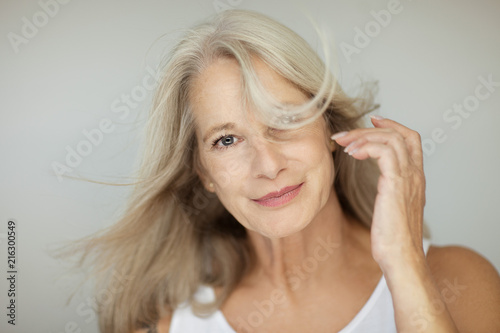 stunning beautiful and self confident best aged woman with grey hair smiling into camera, portrait with white background 