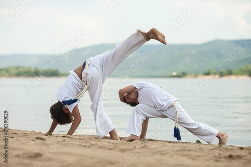 Training of two children on the beach: capoeira, sports