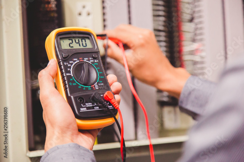 Engineer is measuring voltage or current by voltmeter in control panel