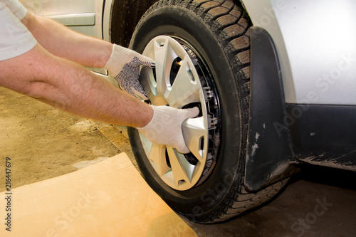 A mechanic removing the hubcap from a car wheel. Tire fitting. Tire service.