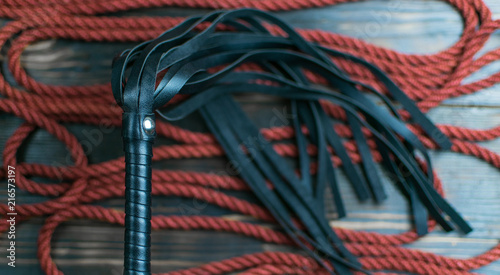 Whip for BDSM and rope to tie on a dark background. Accesories for sexual games.