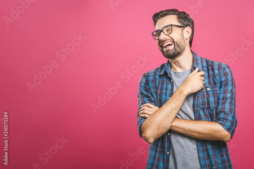 Portrait of a handsome casual man who laughs, standing and laughing over pink background
